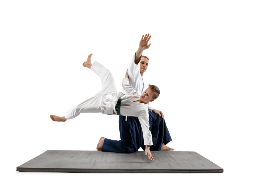 Un adulte et un adolescent pratiquant l'Aikijutsu au Dojo Tanren de Martigny, montrant une technique de projection dans un cadre traditionnel d'arts martiaux japonais en Valais.